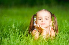 Menina feliz da criança no vestido branco que encontra-se no verão da grama Imagem de Stock Menina feliz da criança no vestido branco que encontra-se no verão da grama Imagem de Stock