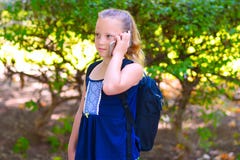 Menina feliz da criança pequena para ir educar e falando no telefone celular no parque da cidade imagens de stock Menina feliz da criança pequena para ir educar e falando no telefone celular no parque da cidade imagens de stock