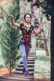 Menina feliz da escola que aprecia a atividade em um parque de escalada da aventura imagens de stock royalty free Menina feliz da escola que aprecia a atividade em um parque de escalada da aventura imagens de stock royalty free