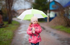 Menina feliz de sorriso pequena com o guarda-chuva verde na mola imagens de stock royalty free Menina feliz de sorriso pequena com o guarda-chuva verde na mola imagens de stock royalty free