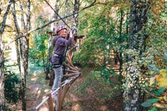 Menina feliz, mulher, engrenagem de escalada em uma aventura, estrada da corda, seguro, atração, parque de diversões, recreação a fotografia de stock royalty free Menina feliz, mulher, engrenagem de escalada em uma aventura, estrada da corda, seguro, atração, parque de diversões, recreação a fotografia de stock royalty free