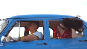 Menina feliz nos óculos de sol que inclinam-se fora da janela de carro retro e que apreciam a viagem Jovem mulher que olha para f filme Menina feliz nos óculos de sol que inclinam-se fora da janela de carro retro e que apreciam a viagem Jovem mulher que olha para f filme