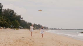 Menina feliz que voa um papagaio, correndo para a câmera com a mãe nova no movimento lento das férias tropicais exóticas da praia filme Menina feliz que voa um papagaio, correndo para a câmera com a mãe nova no movimento lento das férias tropicais exóticas da praia filme