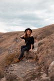 A menina guarda seu chap?u, girando a de volta ao vale com as montanhas sente-se na rocha fotografia de stock A menina guarda seu chap?u, girando a de volta ao vale com as montanhas sente-se na rocha fotografia de stock