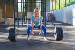 A menina loura faz o deadlift, ombros e a cara é dianteira, gabinete fotografia de stock royalty free A menina loura faz o deadlift, ombros e a cara é dianteira, gabinete fotografia de stock royalty free