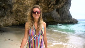 A menina loura nova em um vestido brilhante corre ao longo da praia branca, sorrindo na câmera, desenvolvendo o cabelo video estoque A menina loura nova em um vestido brilhante corre ao longo da praia branca, sorrindo na câmera, desenvolvendo o cabelo video estoque