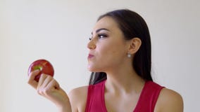 A menina moreno bonita come Apple vermelho em um branco vídeos de arquivo A menina moreno bonita come Apple vermelho em um branco vídeos de arquivo
