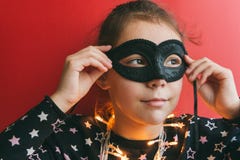 Menina na máscara do disfarce em um fundo vermelho foto de stock Menina na máscara do disfarce em um fundo vermelho foto de stock