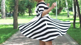 A menina no vestido está andando felizmente com o parque e o giro do verão Retrato de uma menina em um vestido do verão e filme A menina no vestido está andando felizmente com o parque e o giro do verão Retrato de uma menina em um vestido do verão e filme