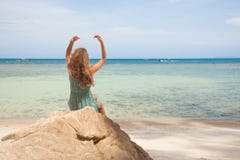 Menina no vestido que senta-se em uma rocha pelo mar foto de stock Menina no vestido que senta-se em uma rocha pelo mar foto de stock