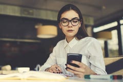Menina nos peritos do funcionamento de vidros que fornecem a campanha de publicidade no Web site popular através do smartphone fotografia de stock royalty free Menina nos peritos do funcionamento de vidros que fornecem a campanha de publicidade no Web site popular através do smartphone fotografia de stock royalty free