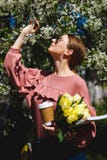 Menina nos óculos de sol e em vidros cor-de-rosa da camiseta com entre as árvores de florescência fotografia de stock royalty free Menina nos óculos de sol e em vidros cor-de-rosa da camiseta com entre as árvores de florescência fotografia de stock royalty free