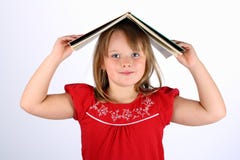 Menina pequena no vermelho que prende um livro em sua cabeça imagem de stock Menina pequena no vermelho que prende um livro em sua cabeça imagem de stock