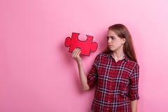 Menina, posses um enigma grande e olhares desapontados novos nele Em um fundo cor-de-rosa Fotografia de Stock Royalty Free Menina, posses um enigma grande e olhares desapontados novos nele Em um fundo cor-de-rosa Fotografia de Stock Royalty Free