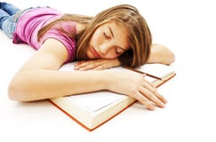 Menina que dorme com sua cabeça em um livro aberto imagem de stock Menina que dorme com sua cabeça em um livro aberto imagem de stock