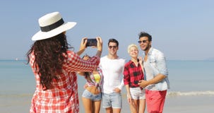 Menina que toma a foto do grupo dos povos na praia no homem alegre feliz e na mulher do telefone esperto da pilha que levantam tu vídeos de arquivo Menina que toma a foto do grupo dos povos na praia no homem alegre feliz e na mulher do telefone esperto da pilha que levantam tu vídeos de arquivo