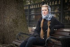 Menina ruivo bonita que senta-se em um banco imagem de stock Menina ruivo bonita que senta-se em um banco imagem de stock
