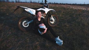 A menina senta-se perto de uma motocicleta e aprecia-se o por do sol vídeos de arquivo A menina senta-se perto de uma motocicleta e aprecia-se o por do sol vídeos de arquivo