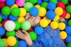 Menino feliz da criança que joga na opinião alta do campo de jogos plástico colorido das bolas Criança engraçada que tem o divert fotos de stock Menino feliz da criança que joga na opinião alta do campo de jogos plástico colorido das bolas Criança engraçada que tem o divert fotos de stock