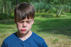 Menino novo que faz uma cara triste fora imagens de stock Menino novo que faz uma cara triste fora imagens de stock