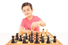 Menino novo que joga a xadrez assentada em uma tabela Imagens de Stock Menino novo que joga a xadrez assentada em uma tabela Imagens de Stock