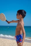 Menino que joga com raquete em uma praia em férias fotos de stock royalty free Menino que joga com raquete em uma praia em férias fotos de stock royalty free