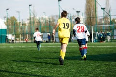 Meninos das equipes de futebol no futebol branco amarelo do jogo do sportswear no campo verde habilidades pingando Jogo de equipe foto de stock Meninos das equipes de futebol no futebol branco amarelo do jogo do sportswear no campo verde habilidades pingando Jogo de equipe foto de stock