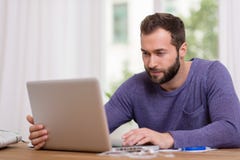 Mens die aan zijn laptop computer thuis werkt Mens die aan zijn laptop computer thuis werkt