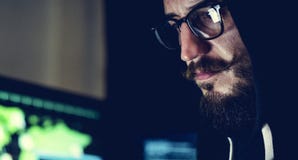Mens die hoodie in computer het binnendringen in een beveiligd computersysteem spruit dragen stock afbeeldingen Mens die hoodie in computer het binnendringen in een beveiligd computersysteem spruit dragen stock afbeeldingen