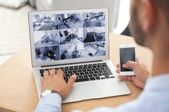 Mens die laptop voor de controle van kabeltelevisie-camera's met behulp van stock fotografie Mens die laptop voor de controle van kabeltelevisie-camera's met behulp van stock fotografie
