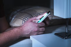 Mens die smartphone in bed laat, in het midden van de nacht gebruiken royalty-vrije stock afbeelding Mens die smartphone in bed laat, in het midden van de nacht gebruiken royalty-vrije stock afbeelding