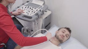 Mens die tijdens het ondergaan van ultrasone klank kenmerkend voor schildklier liggen stock video Mens die tijdens het ondergaan van ultrasone klank kenmerkend voor schildklier liggen stock video