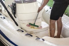 Mens die witte opblaasbare boot met borstel en het systeem van het drukwater wassen bij garage De schipdienst en seizoengebonden royalty-vrije stock afbeelding Mens die witte opblaasbare boot met borstel en het systeem van het drukwater wassen bij garage De schipdienst en seizoengebonden royalty-vrije stock afbeelding