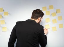 Mens die zich naast een muur met post-its bevinden stock afbeelding Mens die zich naast een muur met post-its bevinden stock afbeelding