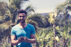 Mensagem latino considerável do homem com o telefone esperto da pilha sobre Forest Background tropical, retrato de Guy Chatting n imagens de stock royalty free Mensagem latino considerável do homem com o telefone esperto da pilha sobre Forest Background tropical, retrato de Guy Chatting n imagens de stock royalty free