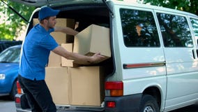 Mensajero de sexo masculino que toma las cajas de la entrega hacia fuera de la furgoneta, compañía móvil, envío de las mercancías imagen de archivo libre de regalías Mensajero de sexo masculino que toma las cajas de la entrega hacia fuera de la furgoneta, compañía móvil, envío de las mercancías imagen de archivo libre de regalías