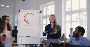 Mentor joven positivo de la mujer de negocios que enseña a los socios multiétnicos, compartiendo experiencia sonriendo en la ofic Mentor joven positivo de la mujer de negocios que enseña a los socios multiétnicos, compartiendo experiencia sonriendo en la ofic