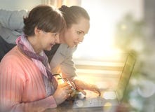 Mer ung kvinna som hjälper en äldre person som använder bärbar datordatoren för internetsökande arkivbild Mer ung kvinna som hjälper en äldre person som använder bärbar datordatoren för internetsökande arkivbild