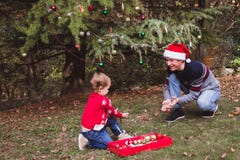 Merry Christmas and Happy Holidays. Father in red Christmas hat and daughter in red sweater decorating the Christmas tree outdoor royalty free stock image Merry Christmas and Happy Holidays. Father in red Christmas hat and daughter in red sweater decorating the Christmas tree outdoor royalty free stock image
