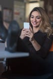 Message de dactylographie d'affaires Jeune femme sûre dans la tenue de détente futée tenant le téléphone intelligent et le regard photo libre de droits Message de dactylographie d'affaires Jeune femme sûre dans la tenue de détente futée tenant le téléphone intelligent et le regard photo libre de droits
