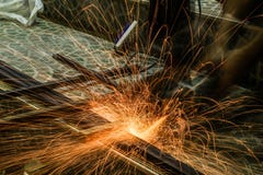 Metallo di taglio dell'operaio con la smerigliatrice Scintilla mentre frantumano il ferro immagini stock Metallo di taglio dell'operaio con la smerigliatrice Scintilla mentre frantumano il ferro immagini stock
