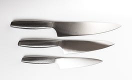 Metta dei coltelli da cucina d'acciaio su fondo bianco fotografia stock Metta dei coltelli da cucina d'acciaio su fondo bianco fotografia stock