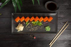 metta dei rotoli di sushi su una banda nera su un fondo di legno nero con le foglie verdi di una pianta da appartamento immagini stock metta dei rotoli di sushi su una banda nera su un fondo di legno nero con le foglie verdi di una pianta da appartamento immagini stock