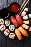 Metta dei sushi freschi di maki, di uramaki e di nigiri, serviti sulla banda nera Vista superiore verticale fotografie stock Metta dei sushi freschi di maki, di uramaki e di nigiri, serviti sulla banda nera Vista superiore verticale fotografie stock