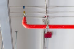 Mettez le feu à l'arroseuse et au tuyau rouge installés sur le plafond pour la sécurité concentrée Images libres de droits Mettez le feu à l'arroseuse et au tuyau rouge installés sur le plafond pour la sécurité concentrée Images libres de droits