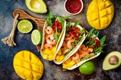 Mexican shrimp tacos with avocado, tomato, mango salsa on rustic stone table. Recipe for Cinco de Mayo party. Top view, overhead, flat lay Mexican shrimp tacos with avocado, tomato, mango salsa on rustic stone table. Recipe for Cinco de Mayo party. Top view, overhead, flat lay