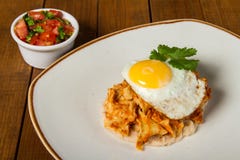 Mexicanska frukostchilaquiles med bönor och det stekte ägget överst, med nya pico de gallo arkivbild Mexicanska frukostchilaquiles med bönor och det stekte ägget överst, med nya pico de gallo arkivbild