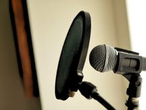 A microphone and pop filter set up in recording studio vocal booth. stock photo A microphone and pop filter set up in recording studio vocal booth. stock photo