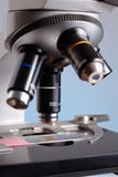 Microscópio em um azul do fundo foto de stock Microscópio em um azul do fundo foto de stock