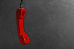 Microtelefono dal telefono rosso della linea terrestre su un fondo grigio della parete immagini stock Microtelefono dal telefono rosso della linea terrestre su un fondo grigio della parete immagini stock